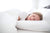 A young girl peacefully sleeping in a white bed with antibacterial Creative Bedding Fossfill Pillow protection.