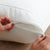 A person adding a zipper to a white pillow for PureCare StainGuard® Cotton Terry Pillow Protector.