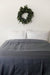 A bed with a Pillowtex Bamboo Duvet Cover for Weighted Blanket and a wreath on the wall is cozy and inviting.