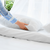 A woman is placing a Down Etc. 25% White Goose Down / 75% White Goose Feather Pillow on the bed to provide support.