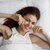 A young woman lying in bed, smiling on her Pillow Factory Comforel Pillow, featured at Sheraton Hotels.