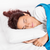 A woman sleeping on an Opulence Cervical Memory Foam Pillow with a blue blanket.