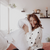 A woman clutching a Holiday Inn® Touch of Down Feather & Down Pillow by Hollander on her hotel bed.